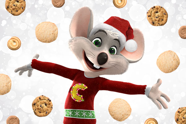 Chuck E Cheese in a holiday sweater and hat with cookies all around