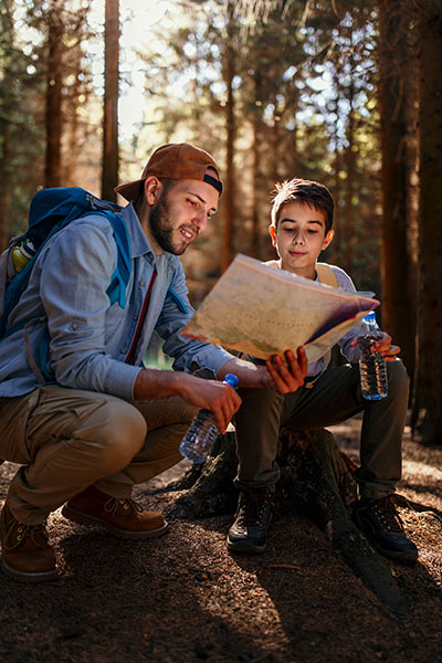 father and son reading map within a forest 