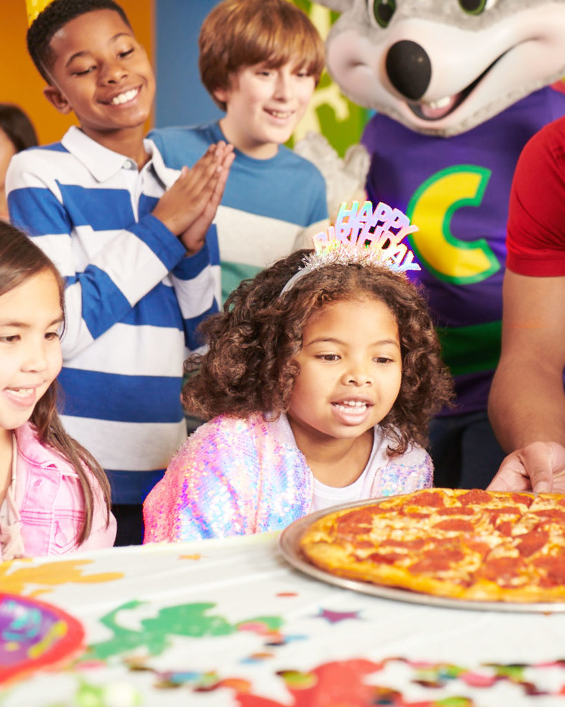 niños a los que se les sirve pizza en una fiesta de cumpleaños