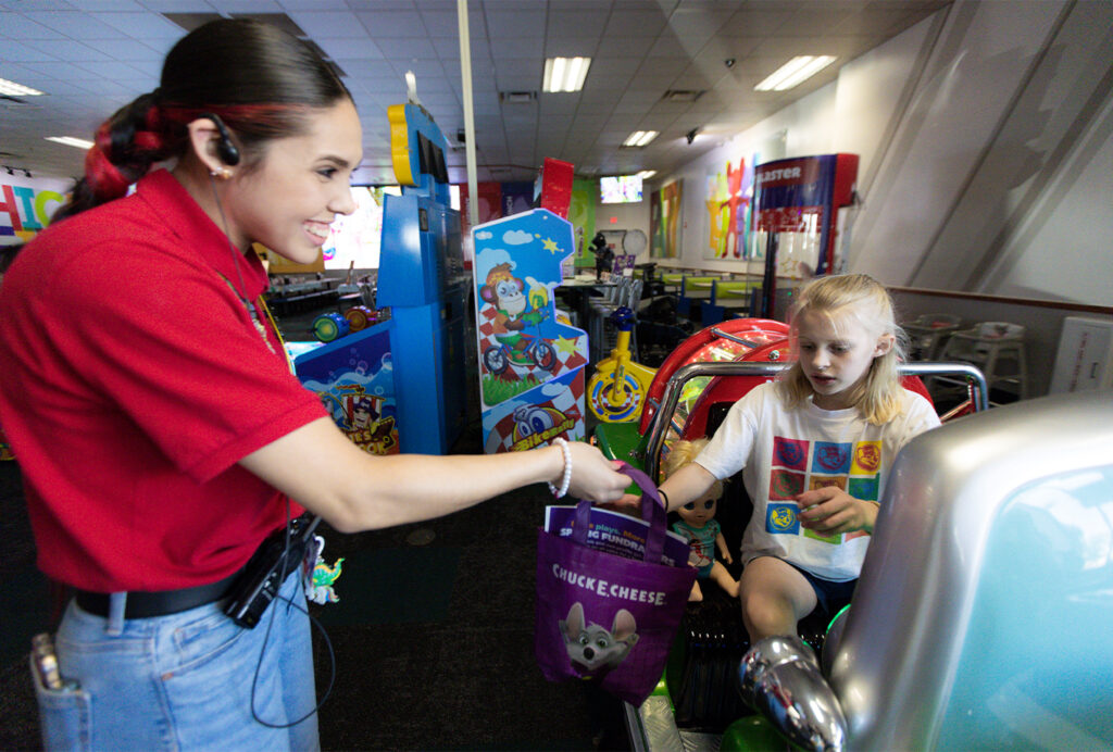 Cast member giving a kid a tote bag during sensory sensitive Sunday