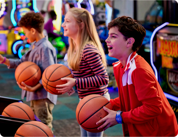 Three kids about to shot some hoops at the basketball throw in the arcade