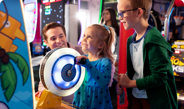 A little girl playing a game with her parent and brother cheering her on