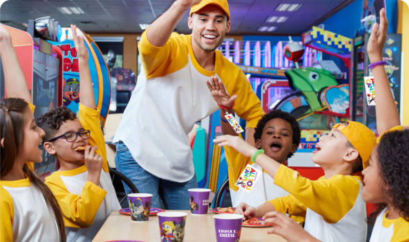 A team in yellow sitting at a table with pizza and beverages about to put their hands all in