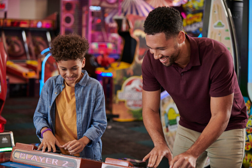Father/son playing in Chuck E. Cheese arcade.