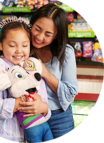 Birthday Girl holding her Chuck E. plush while hugging mom