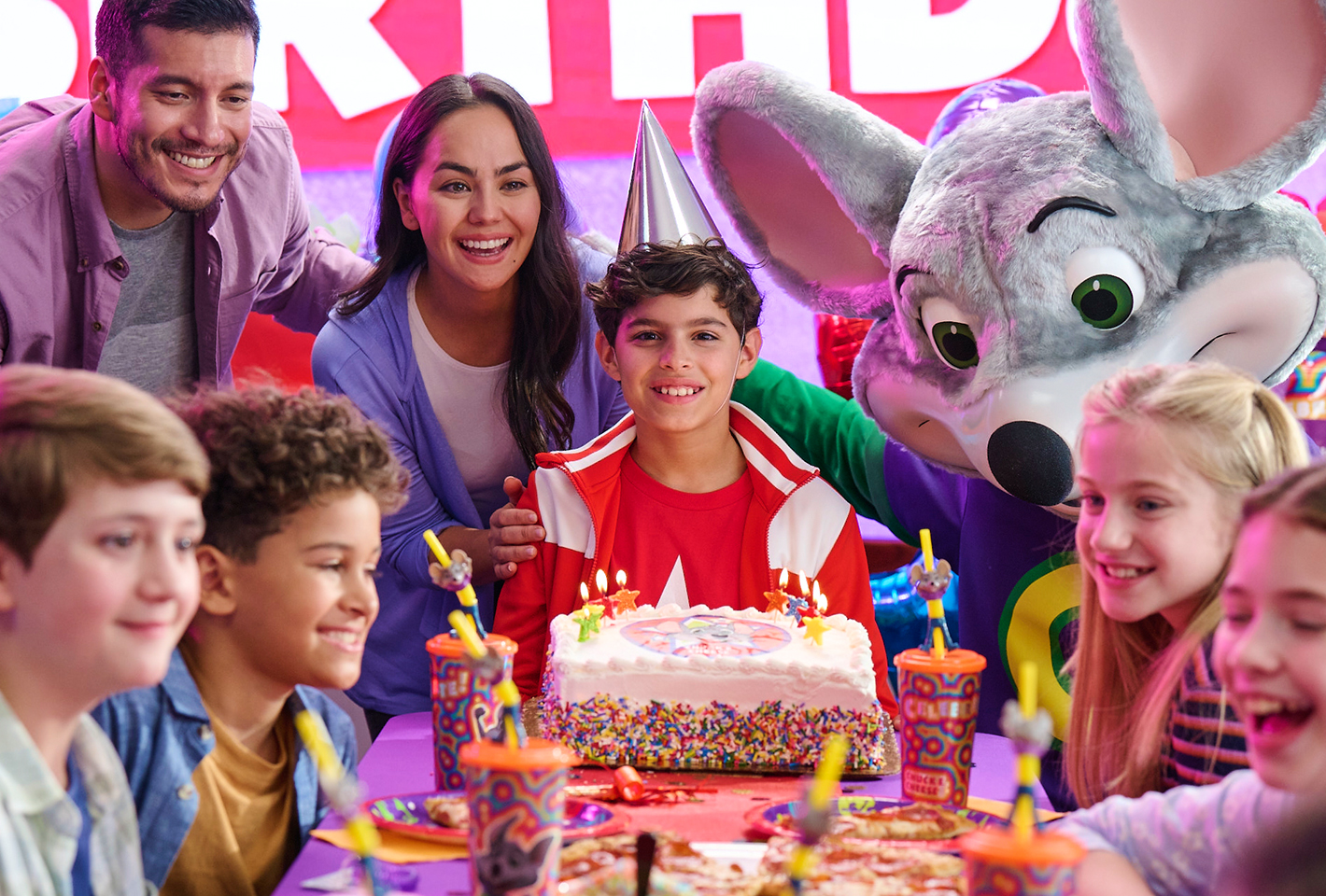 Birthday Boy surrounded by family, friends, cake and Chuck E.