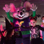 Chuck E. celebrating Halloween with kids on the dance floor.