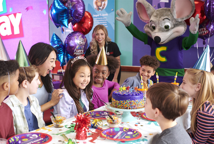 The Birthday receiving her cake with her friends, family and Chuck E. celebrating