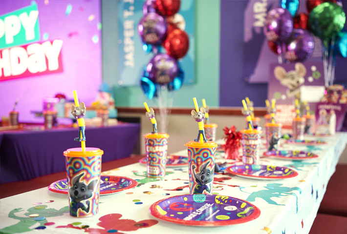 Table set up for a party with cups, plates and balloons