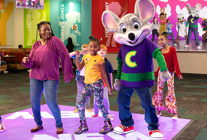 mom with daughter and other kids dancing on interactive dance floor inside chuck e cheese