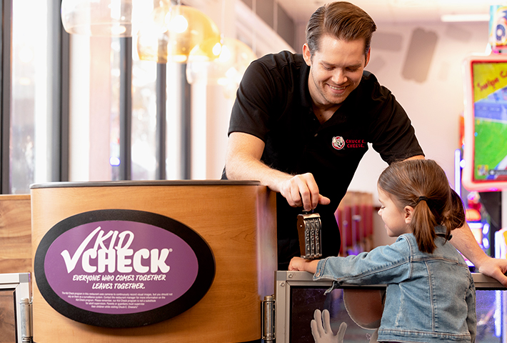 chuck e cheese cast member stamping the arm of a young girl for Kid Check