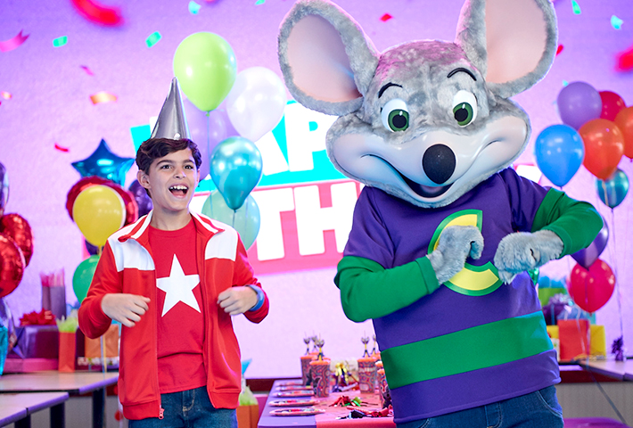 chuck e and birthday child dancing a fun scene with balloons