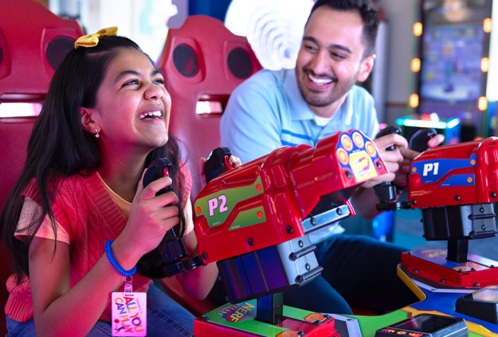 Father and daughter playing a blaster game in the arcade