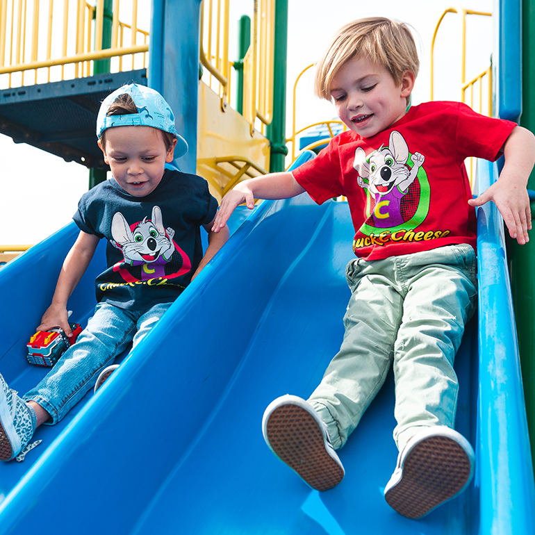 2 young kids sliding down blue slide