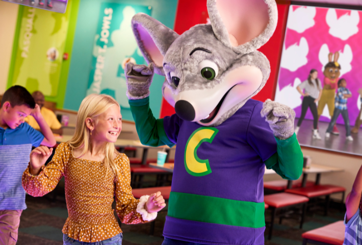 image of chuck E. dancing with child inside Chuck E. Cheese