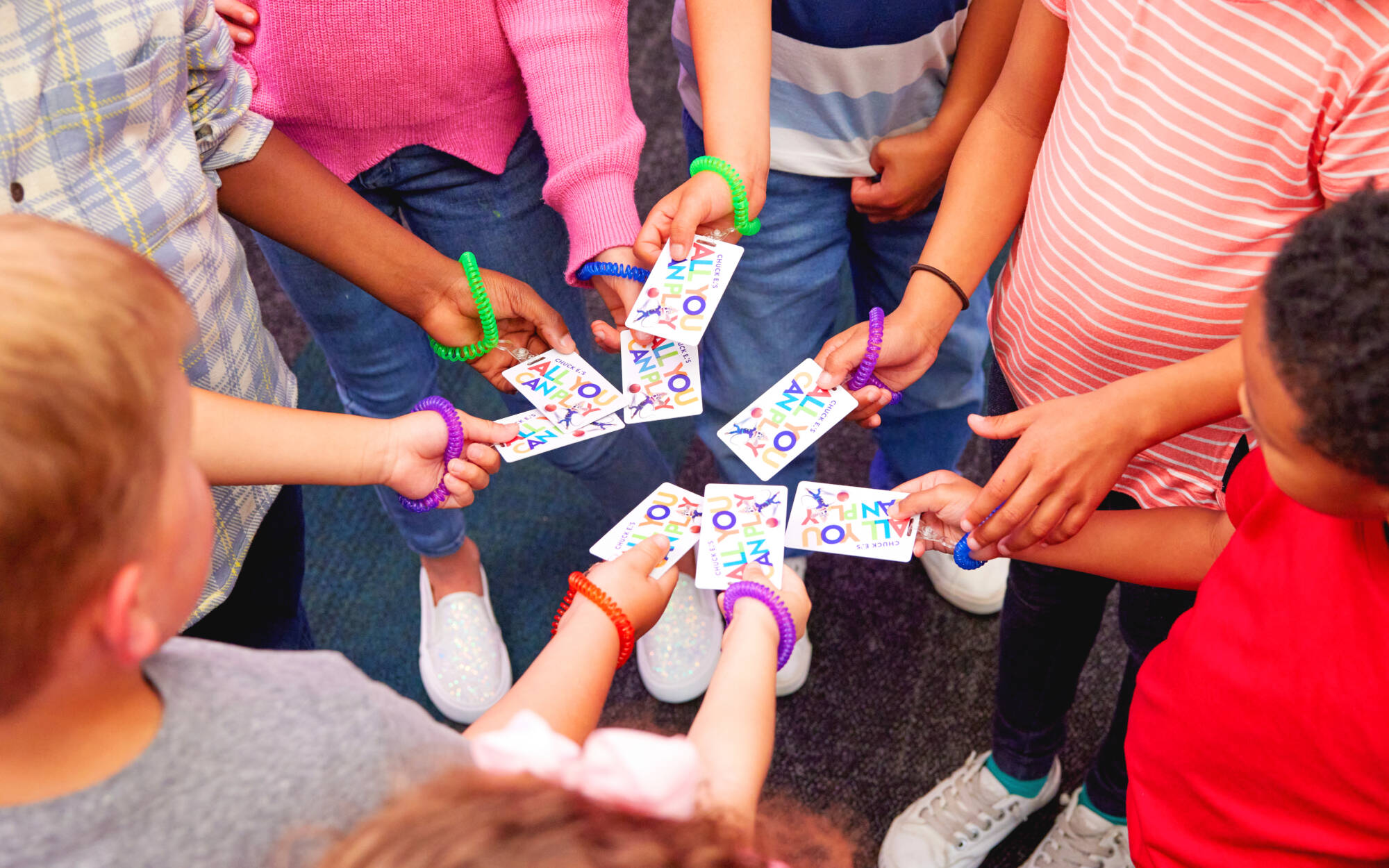 Kids holding fun passes in a circle ready to play at Chuck E. Cheese