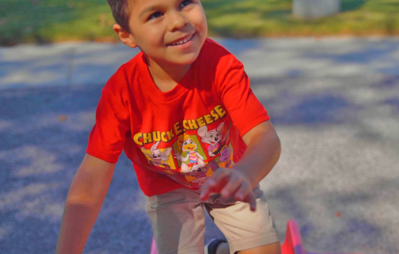 Kid wearing a Chuck E. Cheese t-shirt