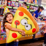 Young girl hugging pizza slice prize.