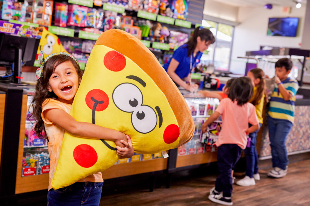 young girl happy holding giant pizza slice plush