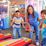 mother playing arcade games with two sons