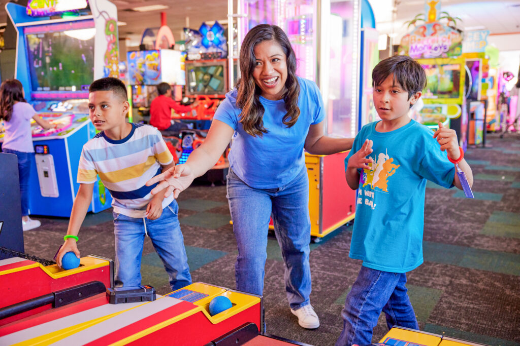 mother playing arcade games with two sons