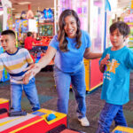 mother playing arcade games with two sons