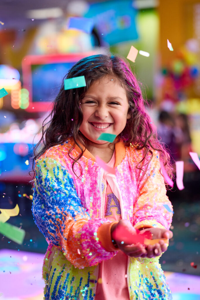 young girl at chuck e cheese birthday party holding confetti