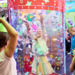 young girl inside chuck e. cheese ticket blaster at a chuck e cheese birthday party with chuck e cheese and friends