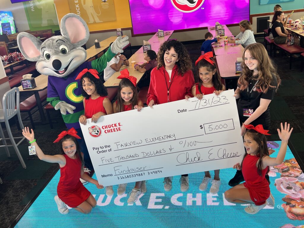 young girls holding donation check with chuck e. cheese