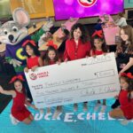 young girls holding donation check with chuck e. cheese