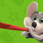 Character Chuck E. blowing horn and green background.