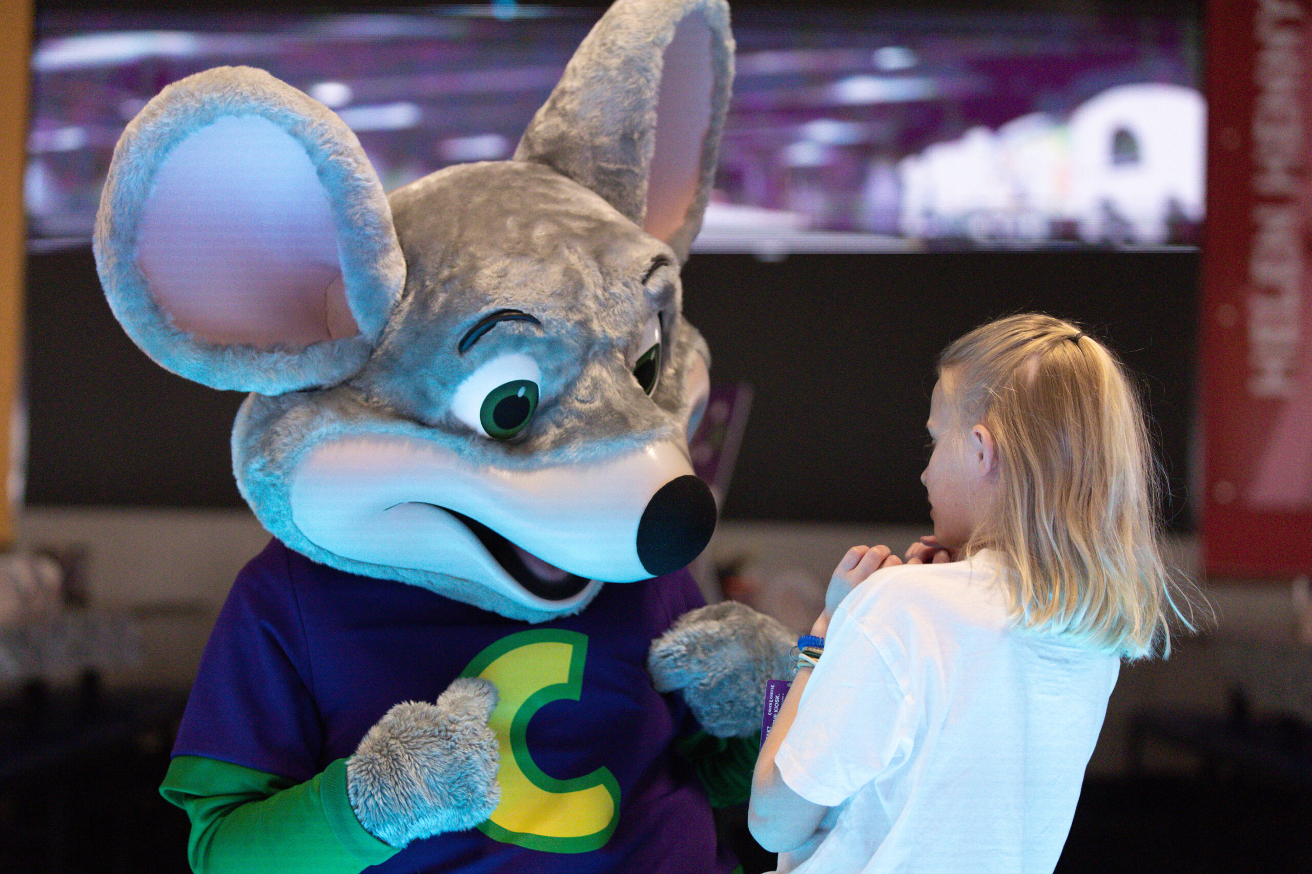 Chuck E playing with child inside chuck e cheese.