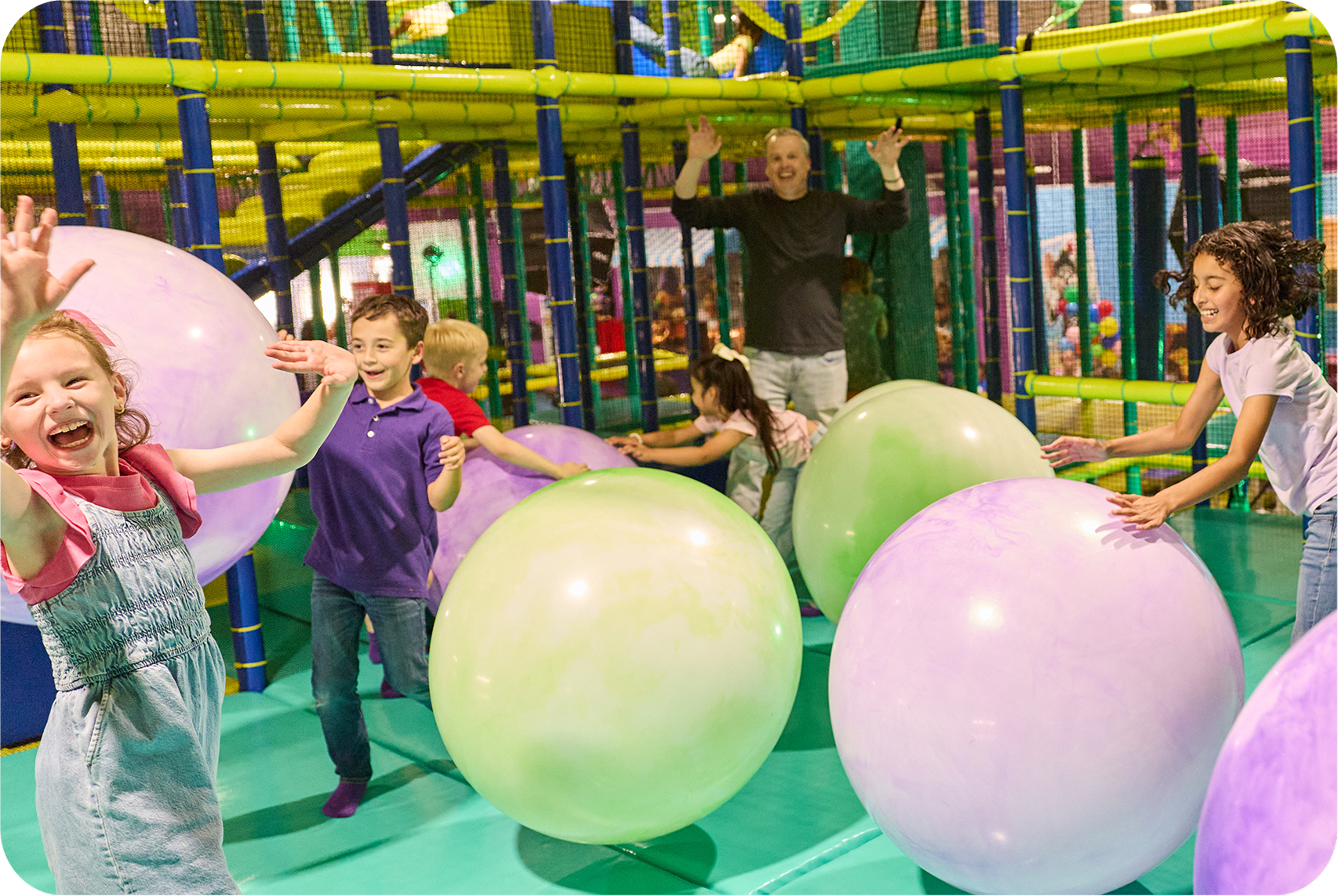 Kids play with pastel inflatable balls among colorful climbing nets at Chuck E. Cheese, a family fun center for kids' birthday parties.