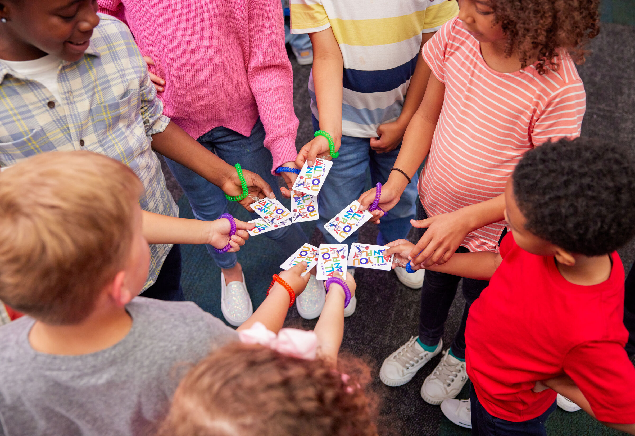 Children at Chuck E. Cheese showing worksheets at a school celebration event