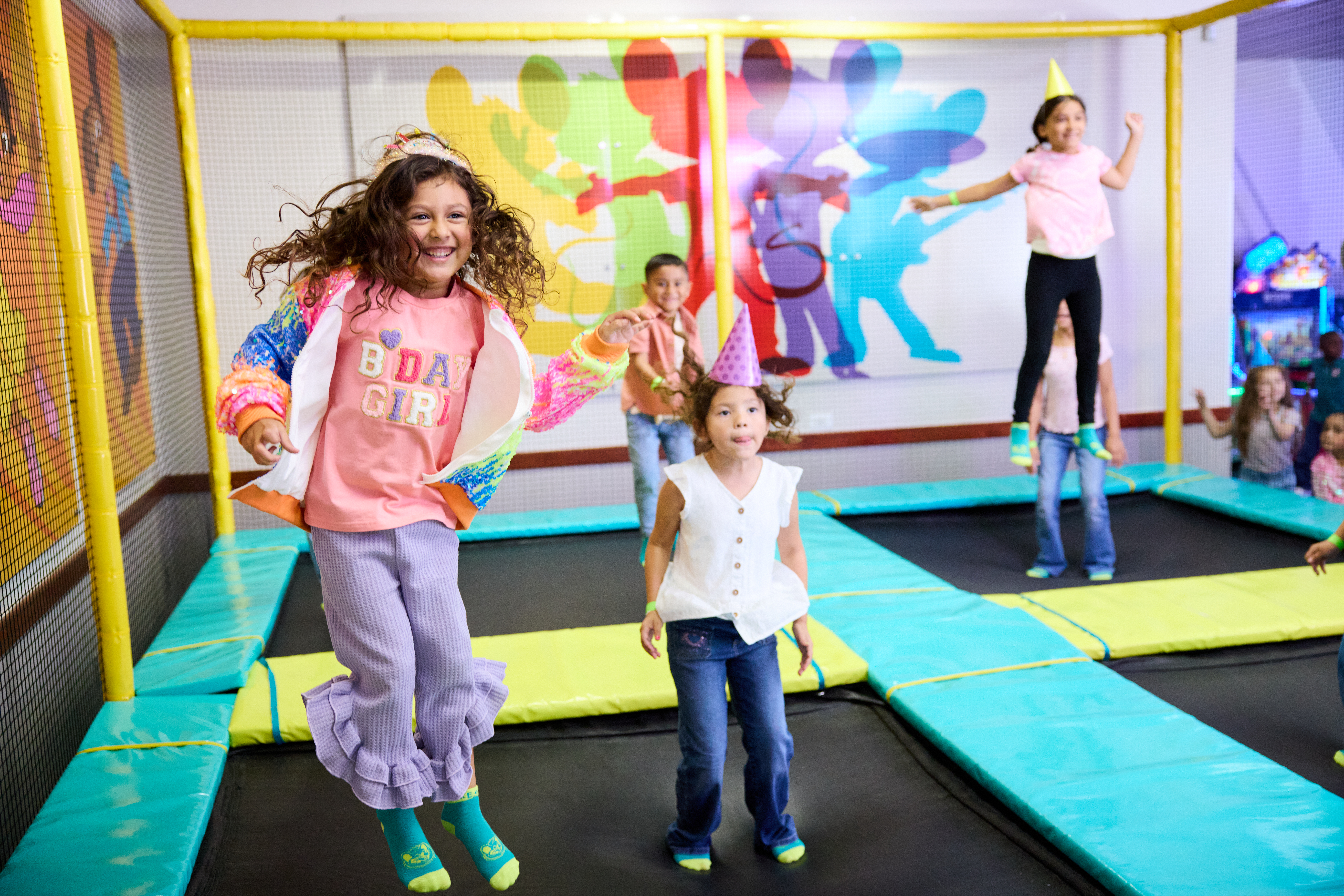 Kids celebrating a birthday party at Chuck E. Cheese Trampoline Zone, jumping with decorations visible