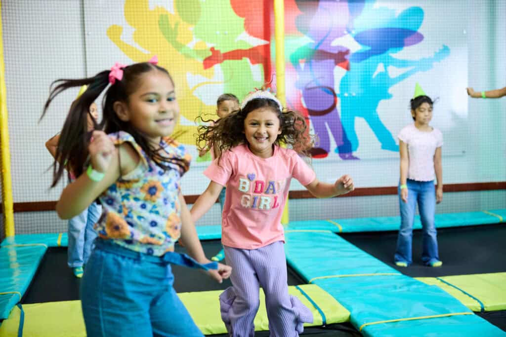 Girls in party outfits bouncing in the Chuck E. Cheese Trampoline Zone