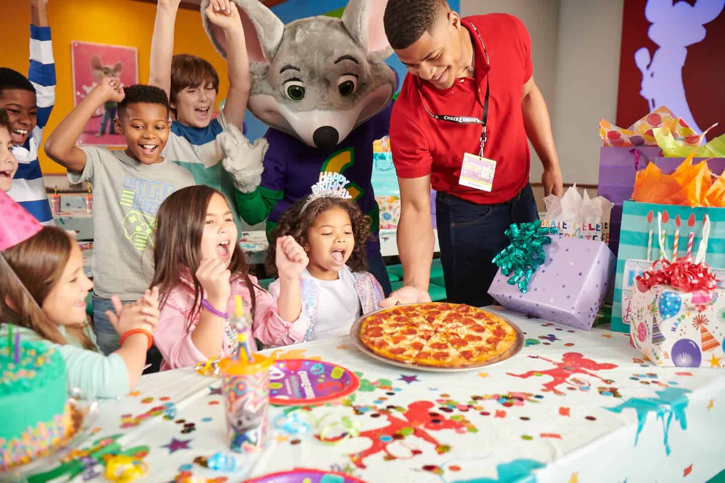 Chuck E. Cheese birthday party in party room, ages 5–8, pizza served, presents and cake on table, Chuck E. joins the fun.