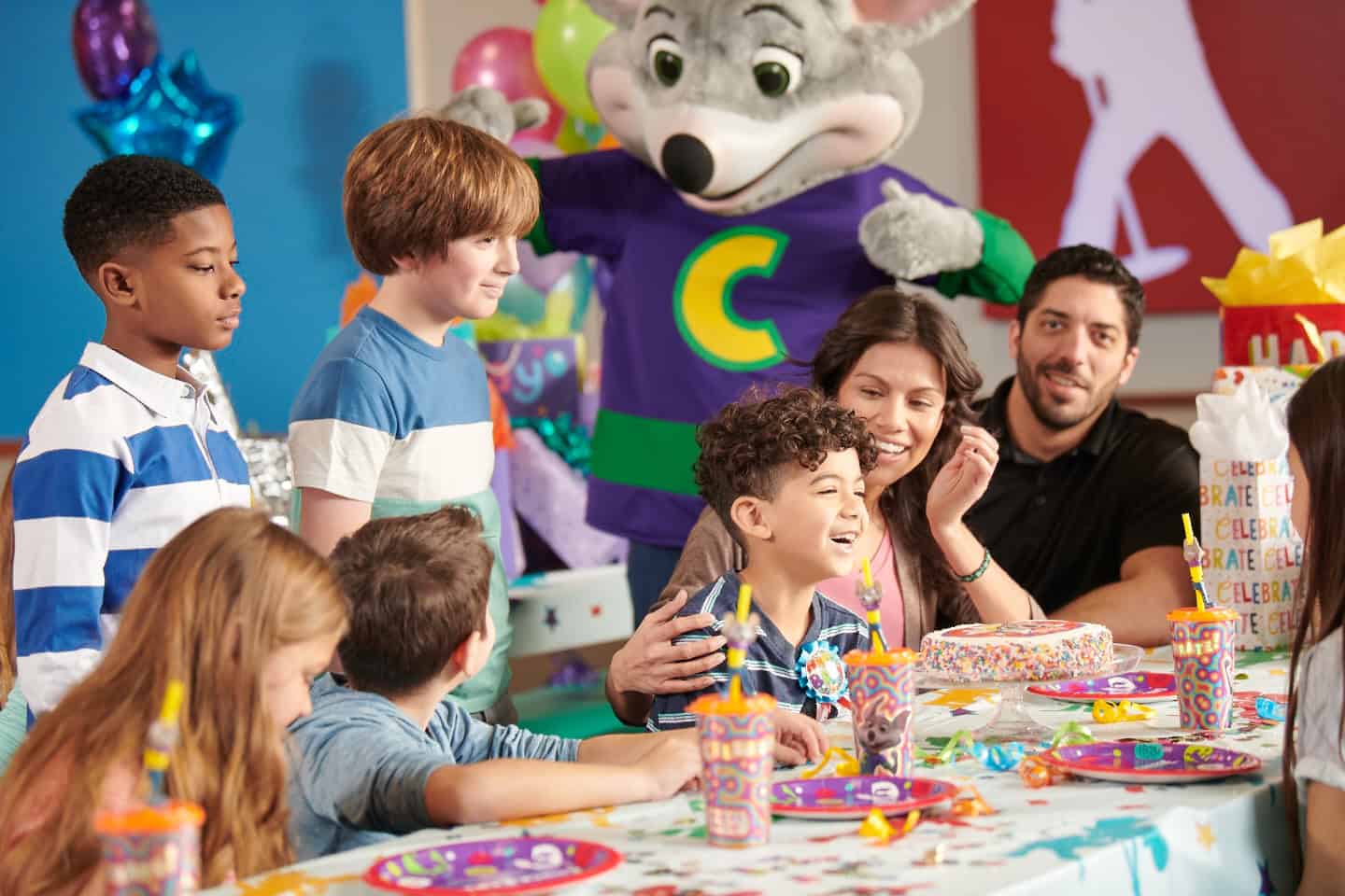 Chuck E. Cheese joins kids in the party room for a birthday with pizza, cake and decorations.