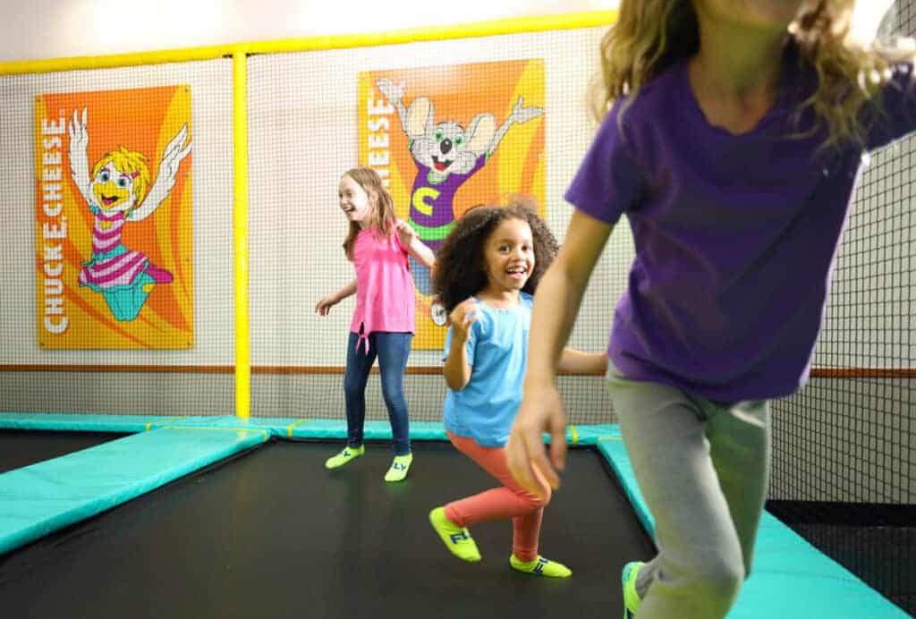 Three girls laughing as they bounce in the Chuck E. Cheese Trampoline Zone