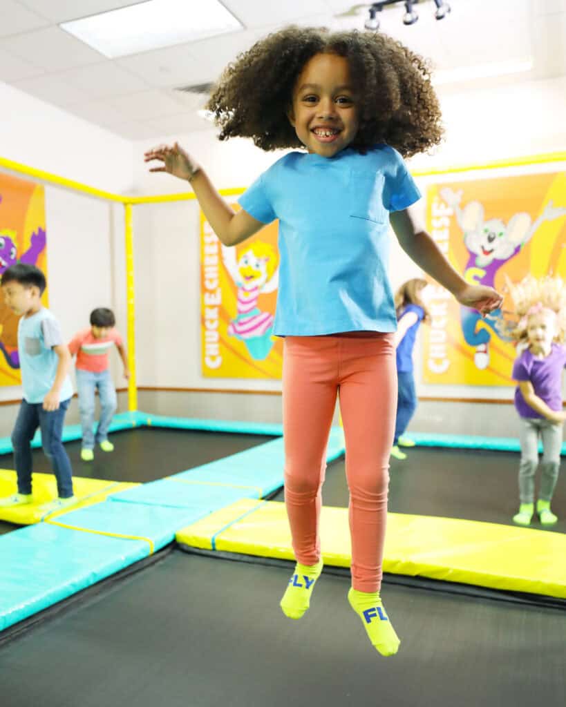 Young girl with curly hair jumping on a trampoline at Chuck E. Cheese