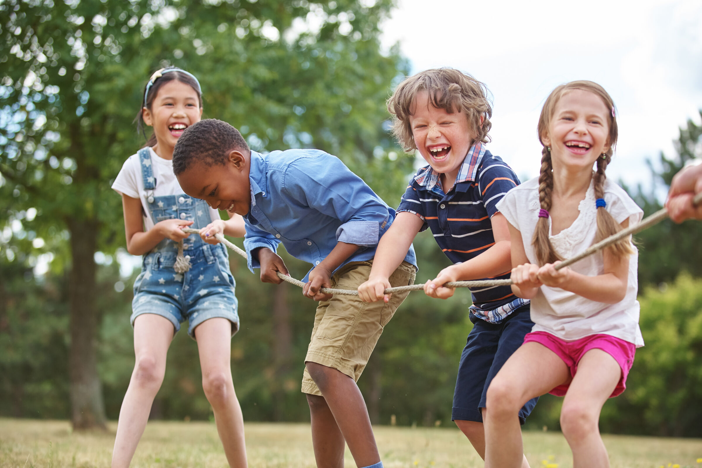 Four kids ages 6–9 laughing and playing together at Chuck E. Cheese