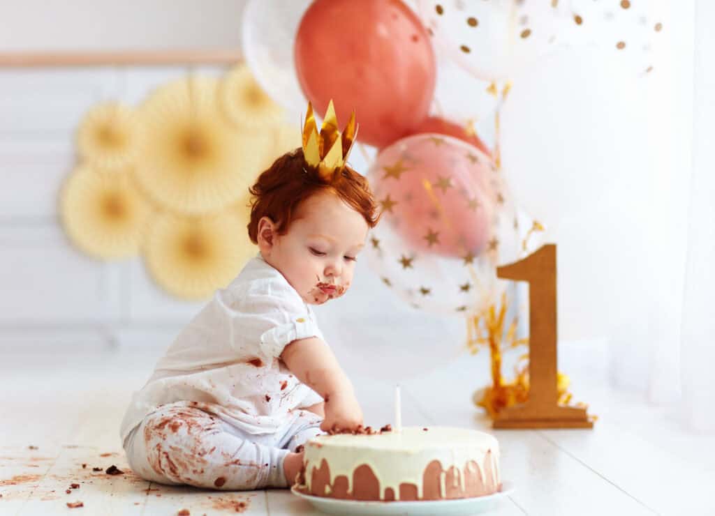 Toddler wearing a gold crown enjoying birthday cake
