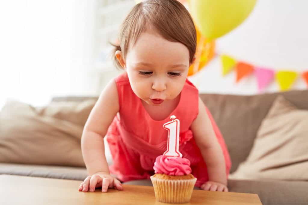 Baby turning one blowing out a cupcake candle at a birthday party