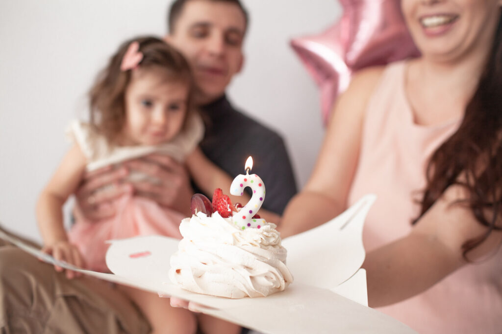 Family with adults and kids at a Chuck&nbsp;E.&nbsp;Cheese birthday party in the party room, host attentive in the background