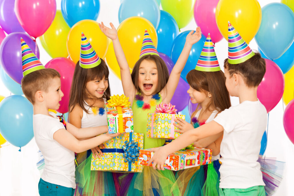 Birthday party in Chuck E. Cheese party room: kids in hats with balloons celebrating.
