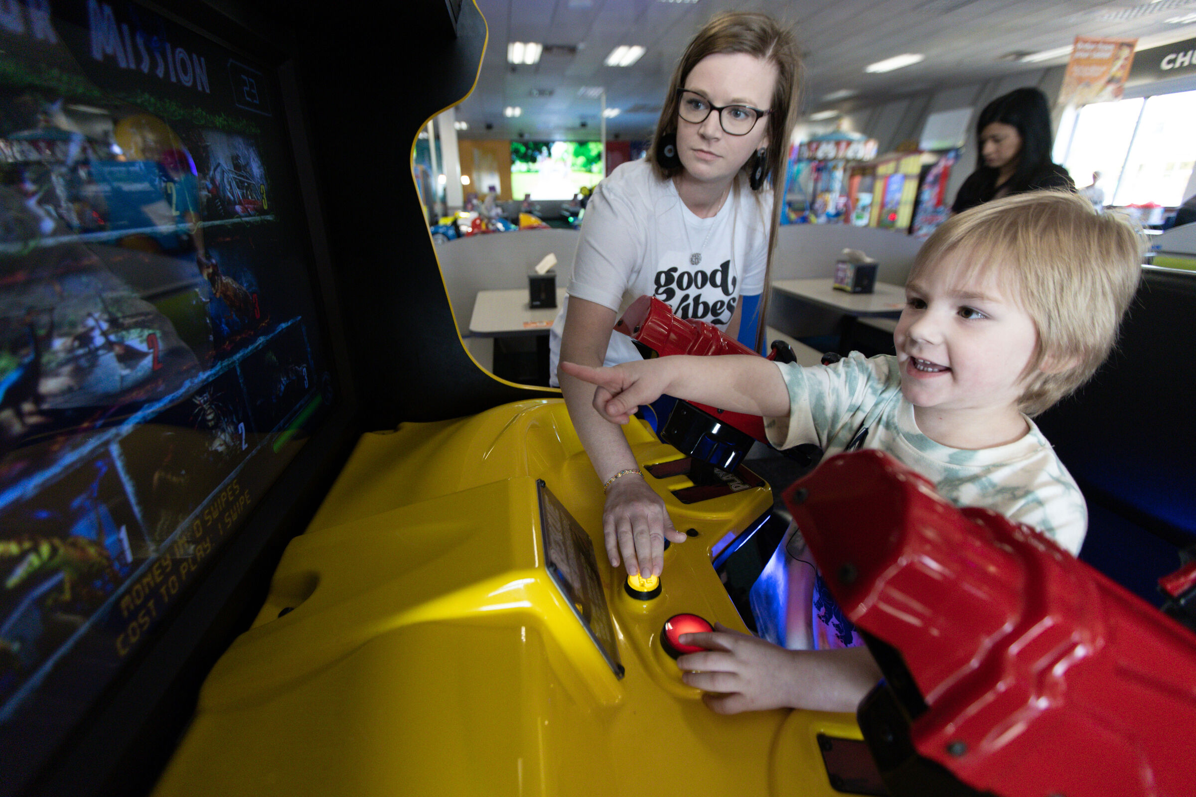 Mom and young child playing an arcade racing game together at Chuck E. Cheese