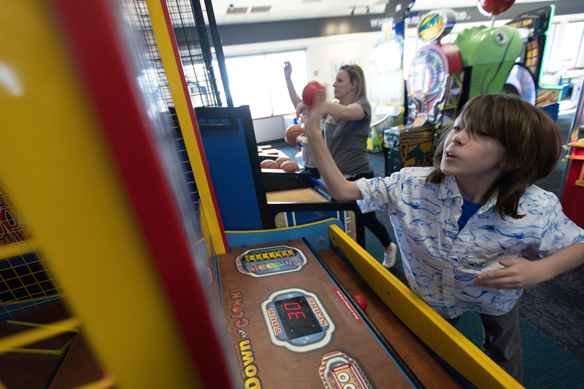 Boy and adult playing a basketball arcade game at Chuck E. Cheese together, both focused on getting a high score.