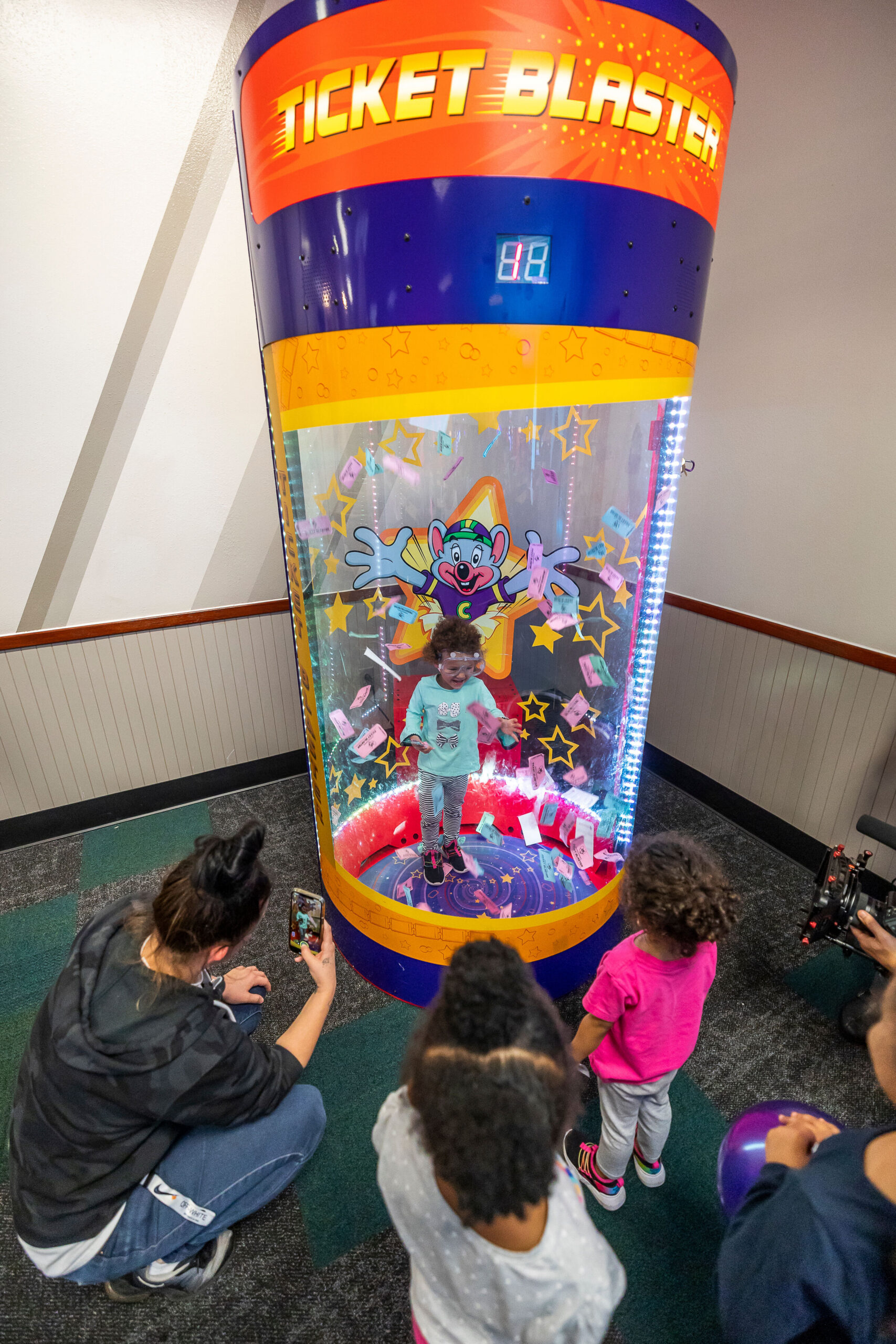 Child playing an arcade game at Chuck E. Cheese, focused on the spinning wheel of a ticket redemption game.