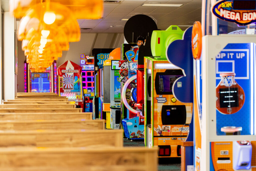 Rows of colorful arcade games and dining tables at Chuck E. Cheese, ready for family fun.