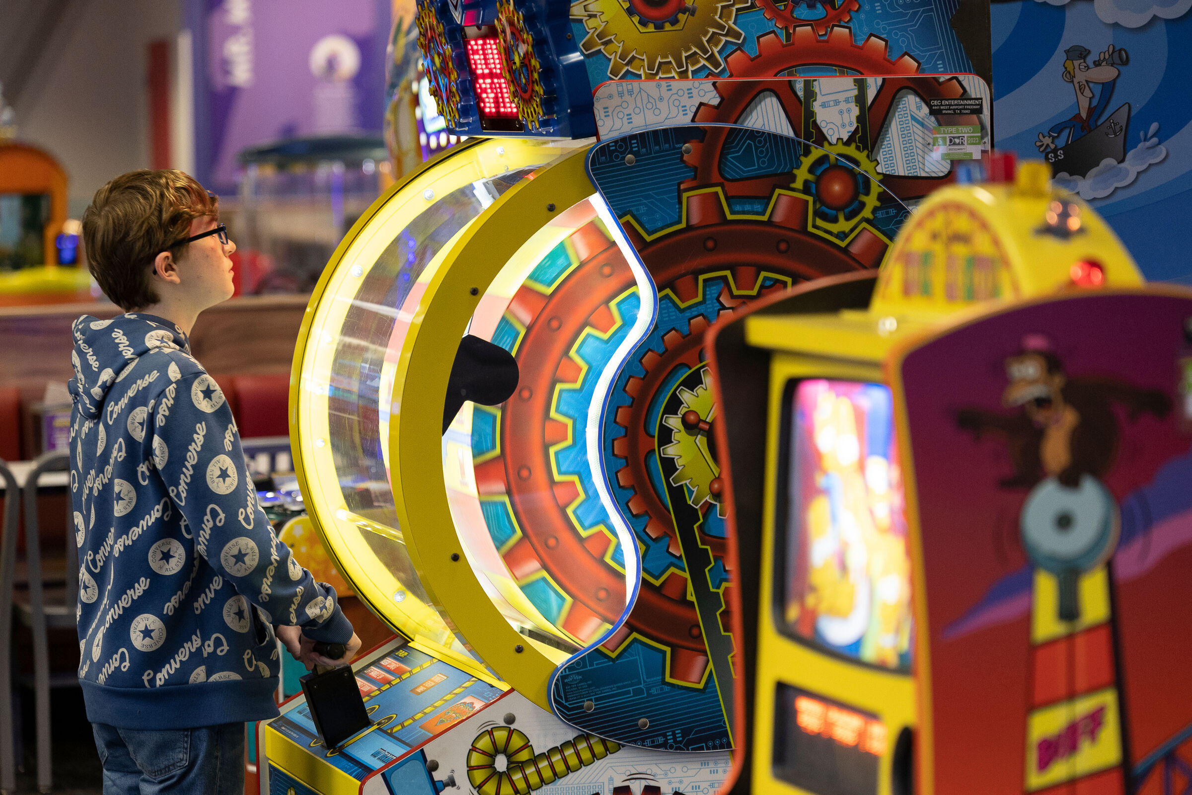 Boy playing an arcade game at Chuck E. Cheese, focused on the spinning wheel of a ticket redemption game.